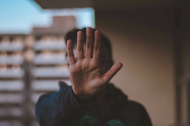 Person with a hand in front of their face as if to say "stop."